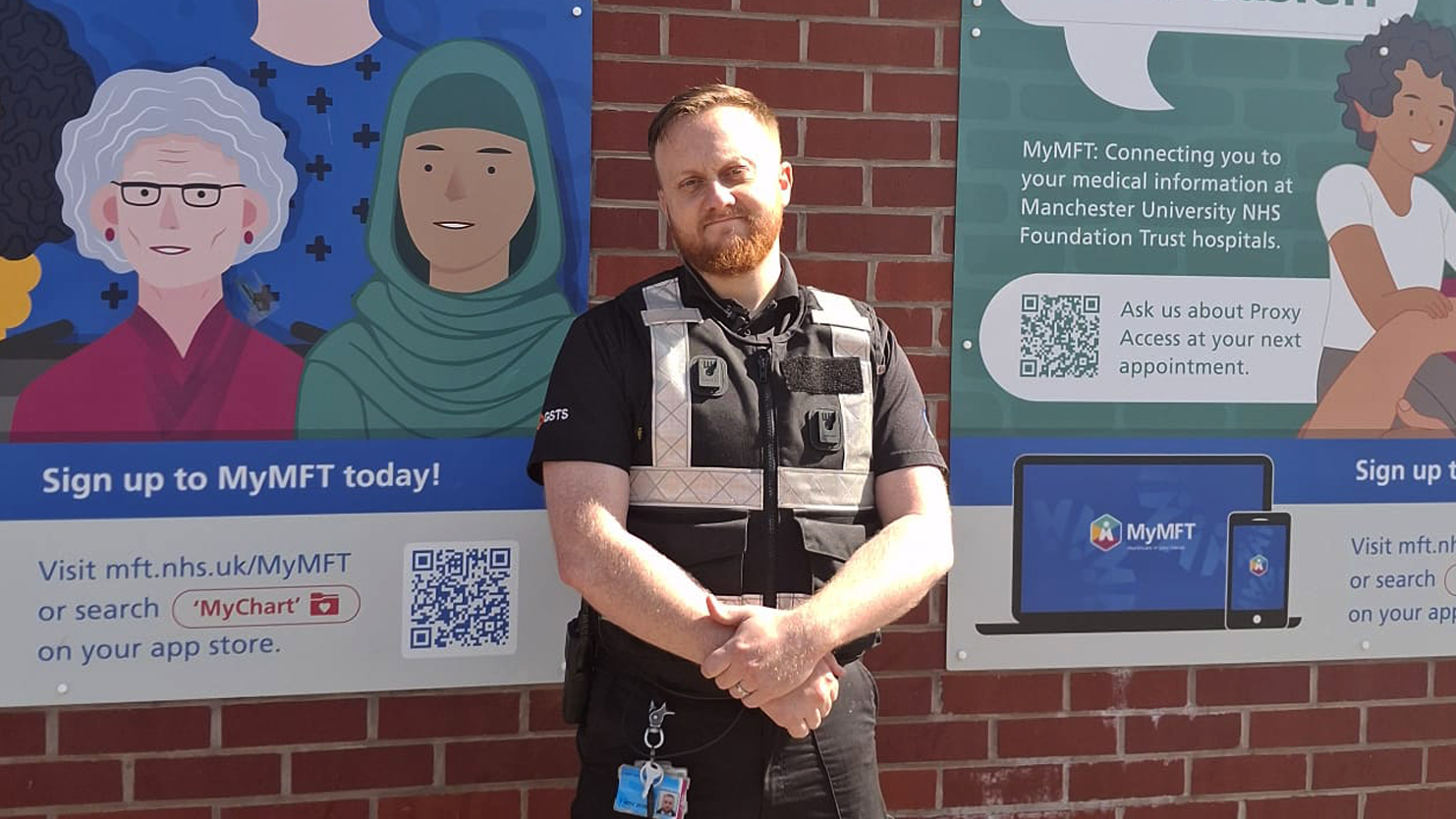 GSTS officer standing near MyMFT sign at Manchester Royal Infirmary during the marathon