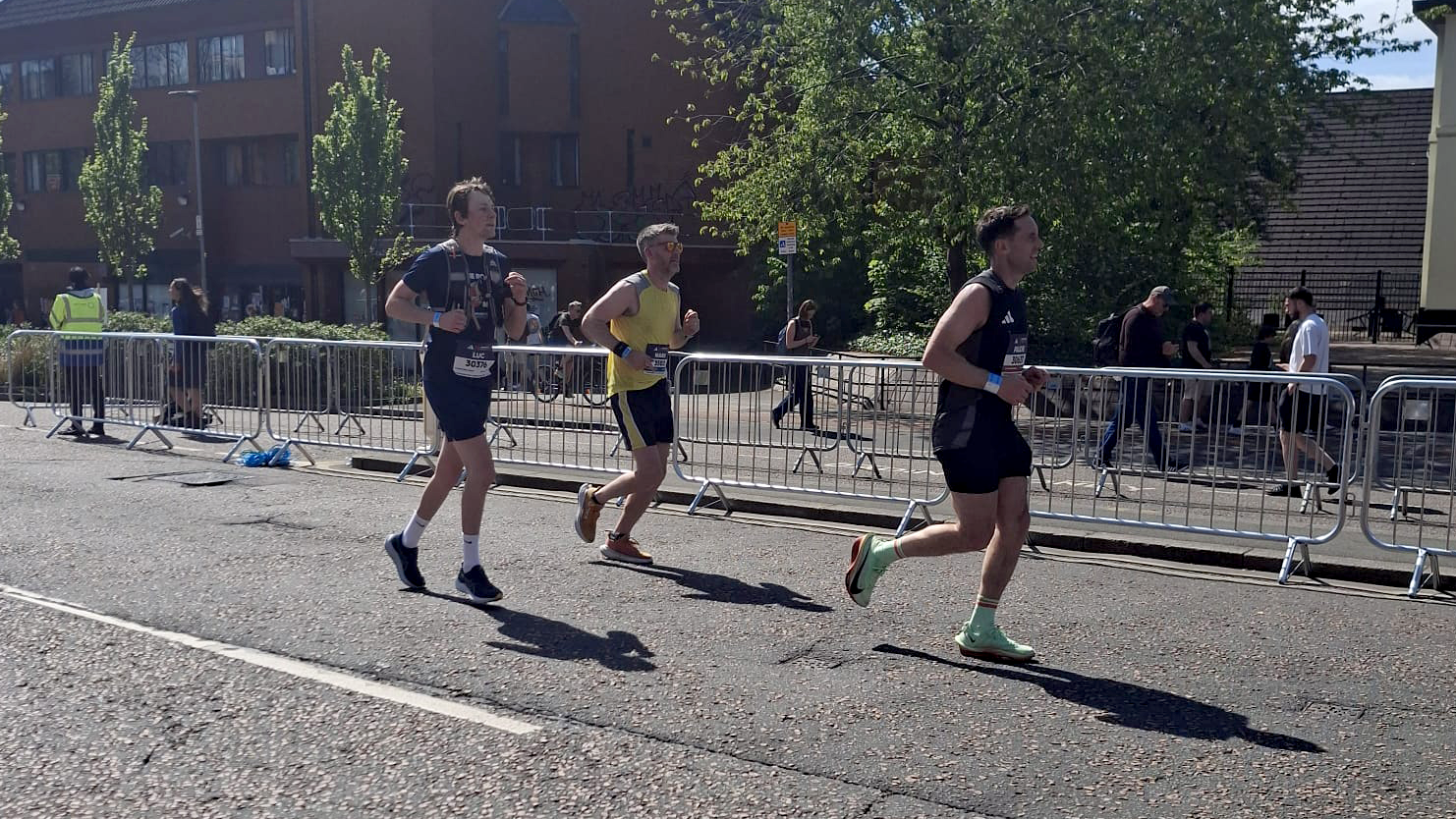 Participants running during the 2025 Manchester Marathon with security barriers in place